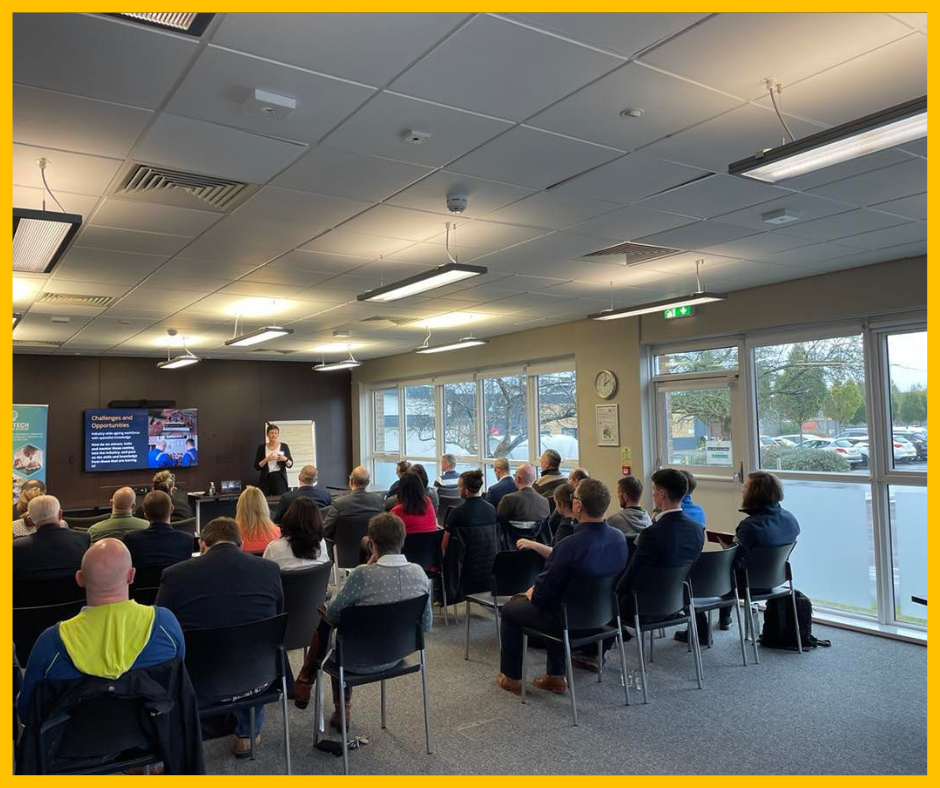 Image shows a meeting room where people are sat down listening to Kate Houlden from Like Technologies speak at the recent ElecTech event